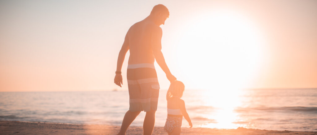 father and daughter walking along shoreside